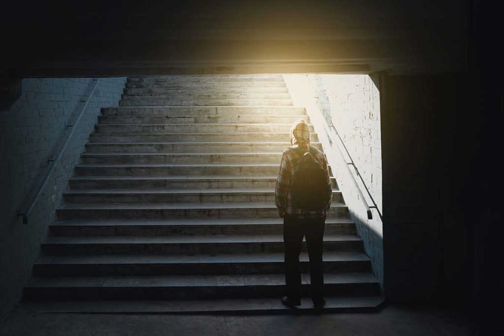 a operson enters a lit staircase thinking of beating drug addiction