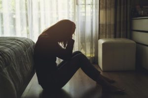 a person sulks on the floor potentially struggling with alcohol use after pregnancy loss