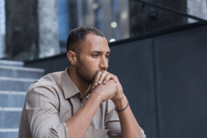 young man seated on couch with his head in his hands and pondering what counts as a relapse.