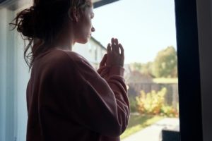 a person looks out of a window potentially thinking about can alcohol cause anemia