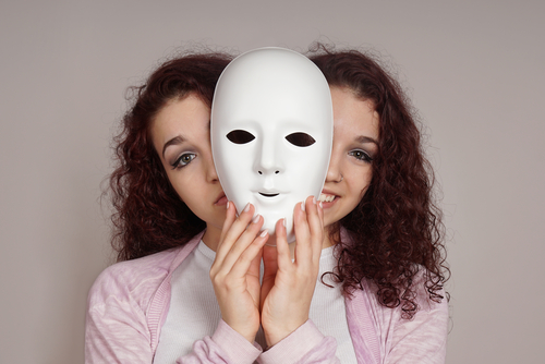 woman hides behind mask