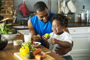 man teaches child how to cook and eat healthy