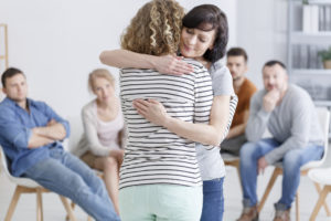 woman comforts other woman at alcohol addiction treatment center
