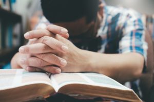 man prays on holy book