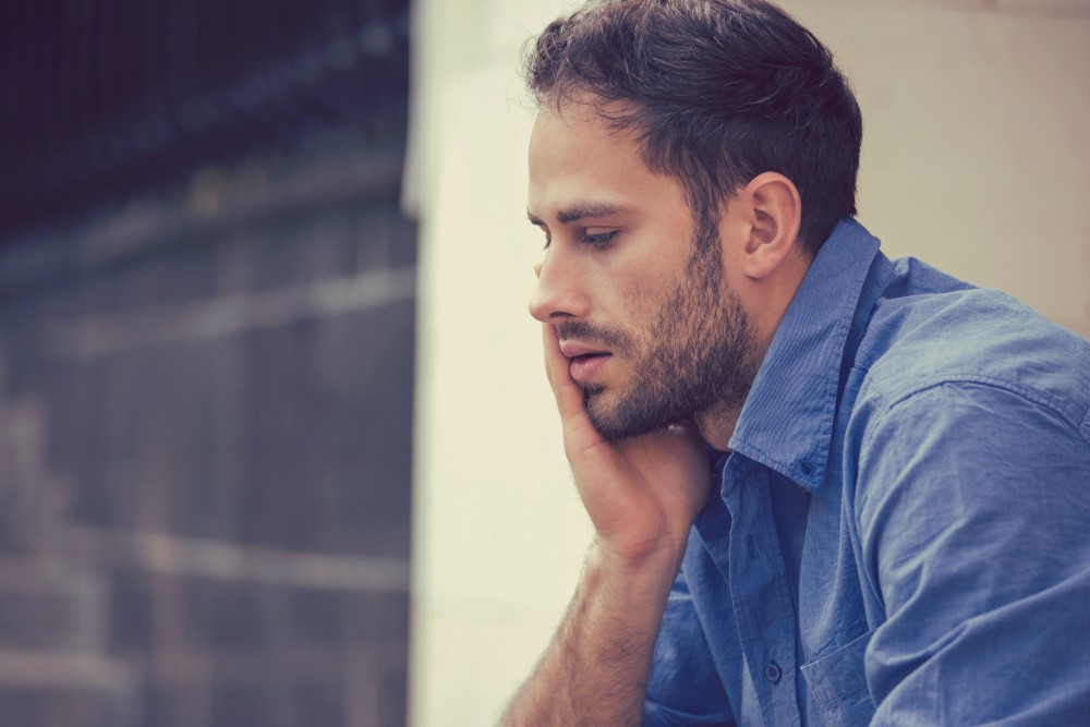 man feels stress from relapse triggers