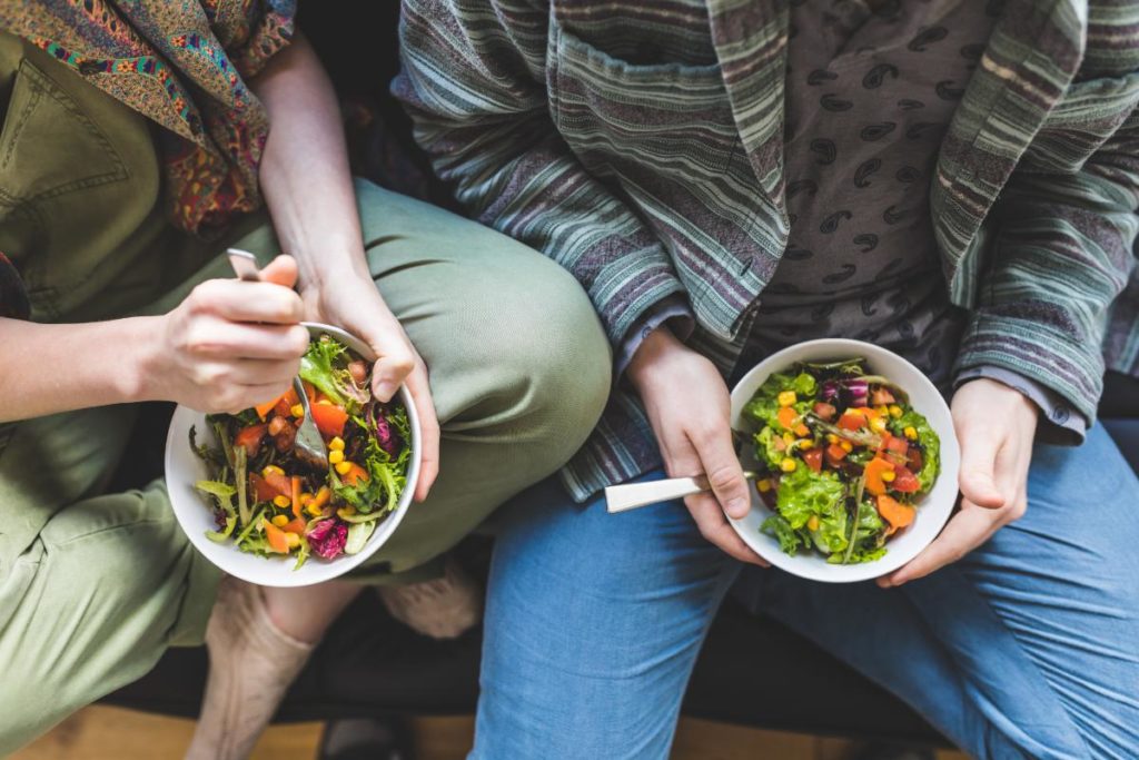 two people sit and eat salads after learning skills in a nutrition therapy program