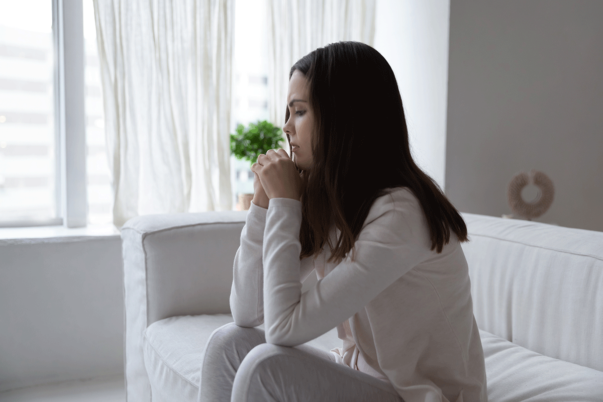 young woman seated on couch in addiction counselor's office crying softly as she learns the three heroin addiction signs you should know