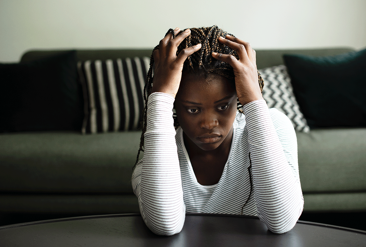 young woman with her head in her hands and looking distraught as she wrestles with the signs of opioid dependence