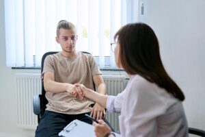 therapist shaking the hand of a young male client as she explains the benefits of residential treatment