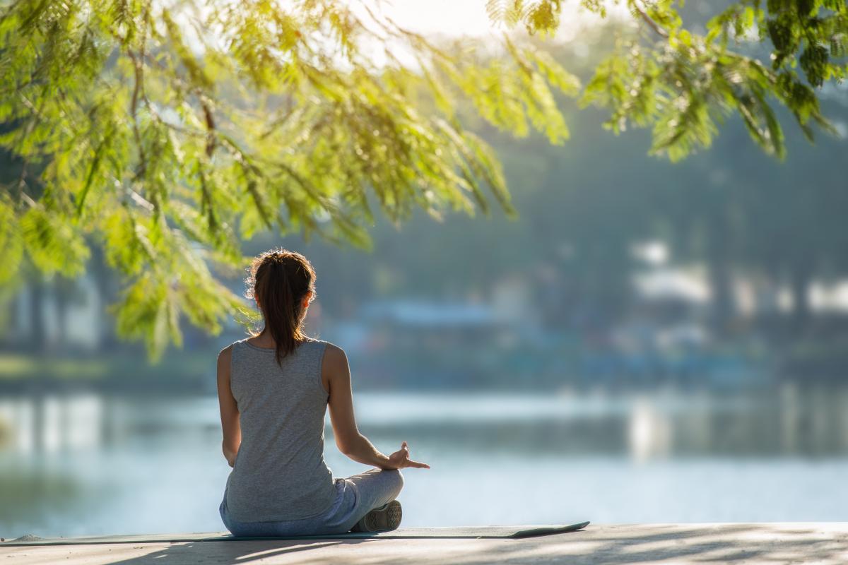 young woman seated outside at a park practicing self-care activities to help with anxiety