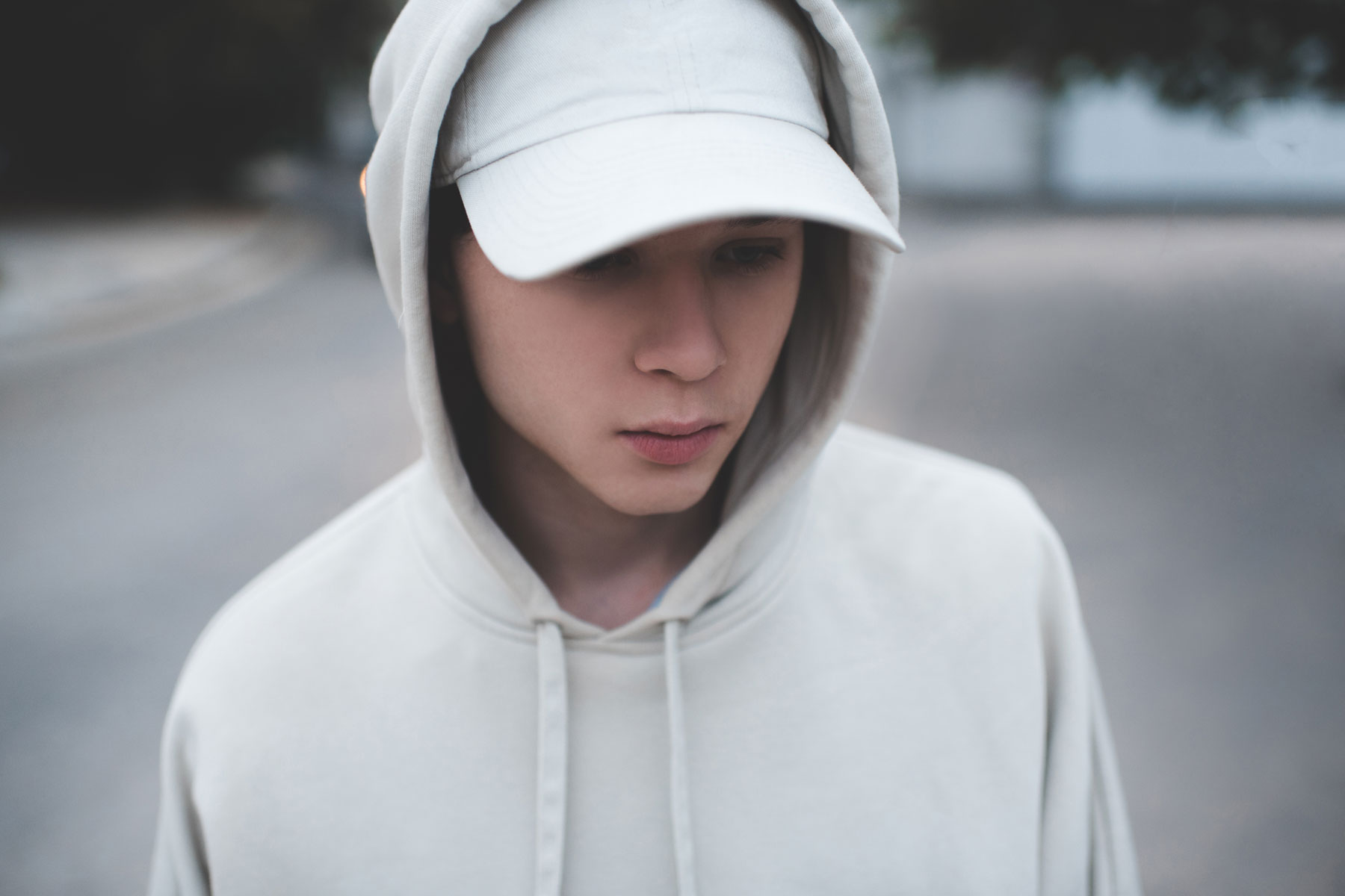 young adult outside alone with ball cap and hoodie looking thoughtful as the contemplate, 'What is fentanyl?"