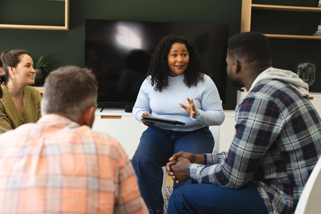 men and women gathered together in a group and discovering what is an addiction alumni program and how can it help maintain sobriety.