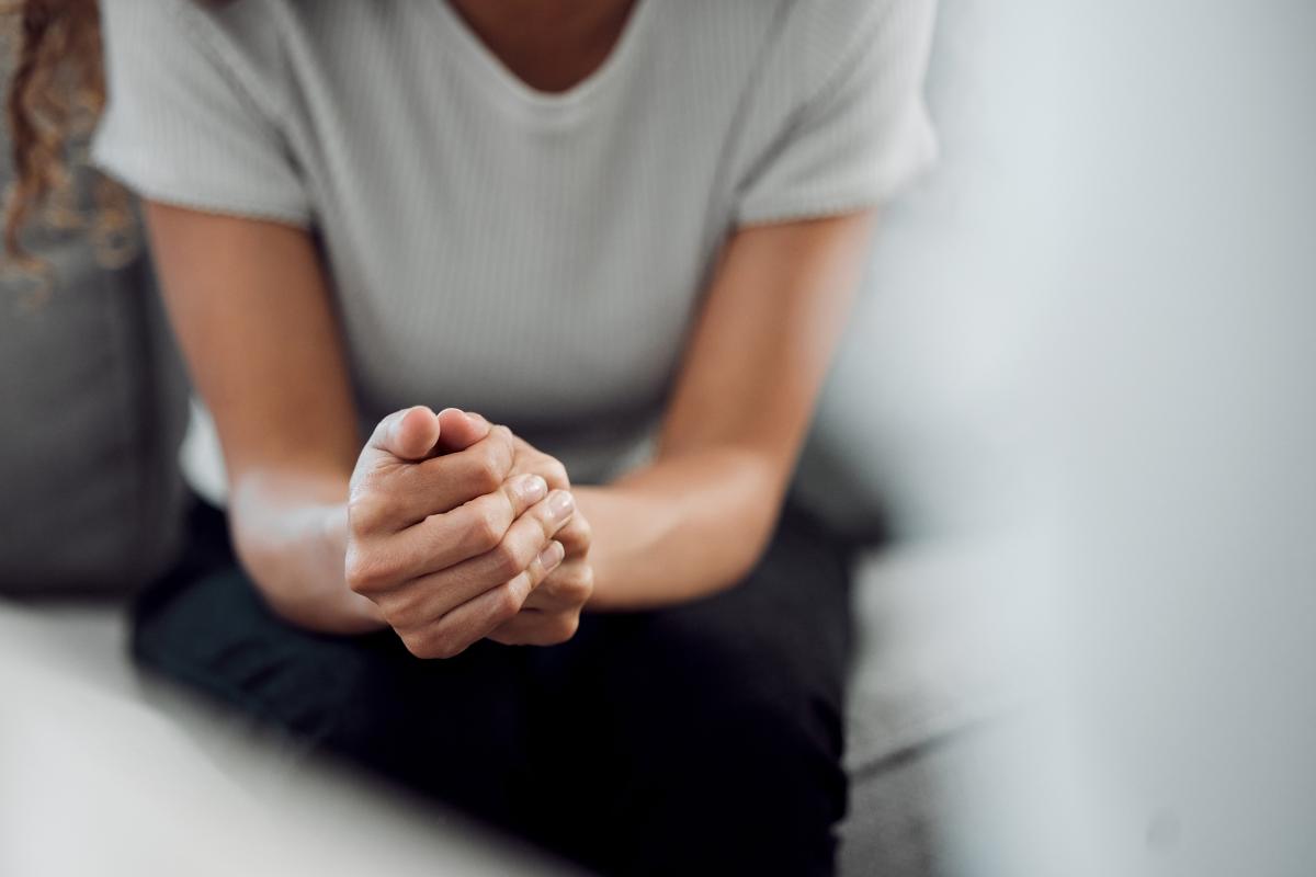 woman sitting pensively with her hands folded as she contemplates the signs of prescription drug abuse