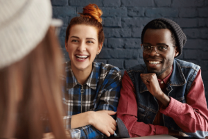 group of young men and women laughing and smiling while discussing the importance of maintaining sobriety