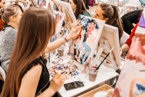 young woman participating in a paiting class as part of a group sessiong and realizing one of 5 benefits of art therapy for addiction recovery