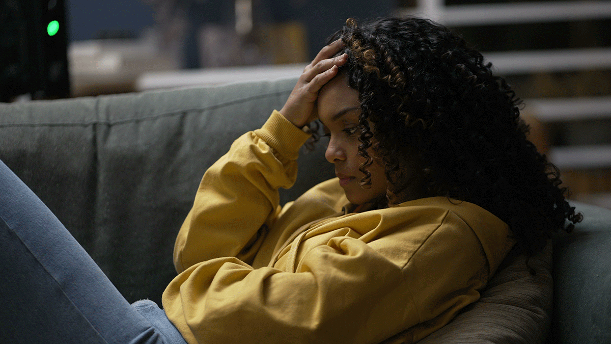 tired looking young woman reclining on couch with her head in her hand not recognizing the signs of fentanyl addiction in herself