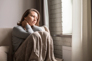 young woman seated alone in her room and staring thoughtfully out the window as she contemplates how to detox safely