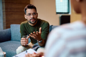 therapist speaking with young man in office setting about how to find the right men's rehab near Austin, Texas.