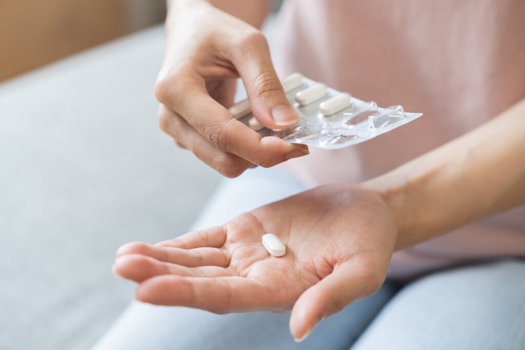 Close-up of a person taking a white pill from a blister pack and holding it in their palm, preparing to take medication.