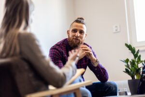 Man with beard listens and talks during a one-on-one therapy session.