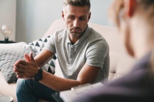 Man in a grey polo discusses concerns with a therapist during a counseling session.